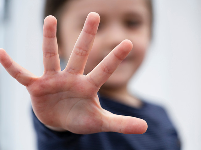 Dziecko pokazuje pięć palców u dłoni, liczy pięć wskazówek, jego twarz jest zamazana