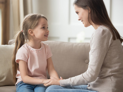 Uśmechnięte mama i córka na sofie rozmawiają o alergiach i Aleric spray do nosa